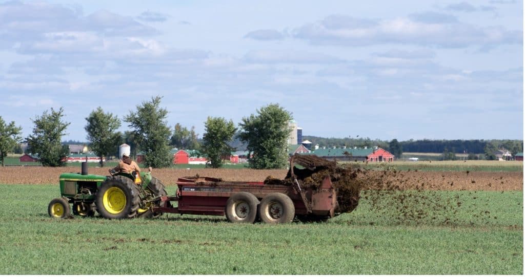 tractor with manure spreader in field